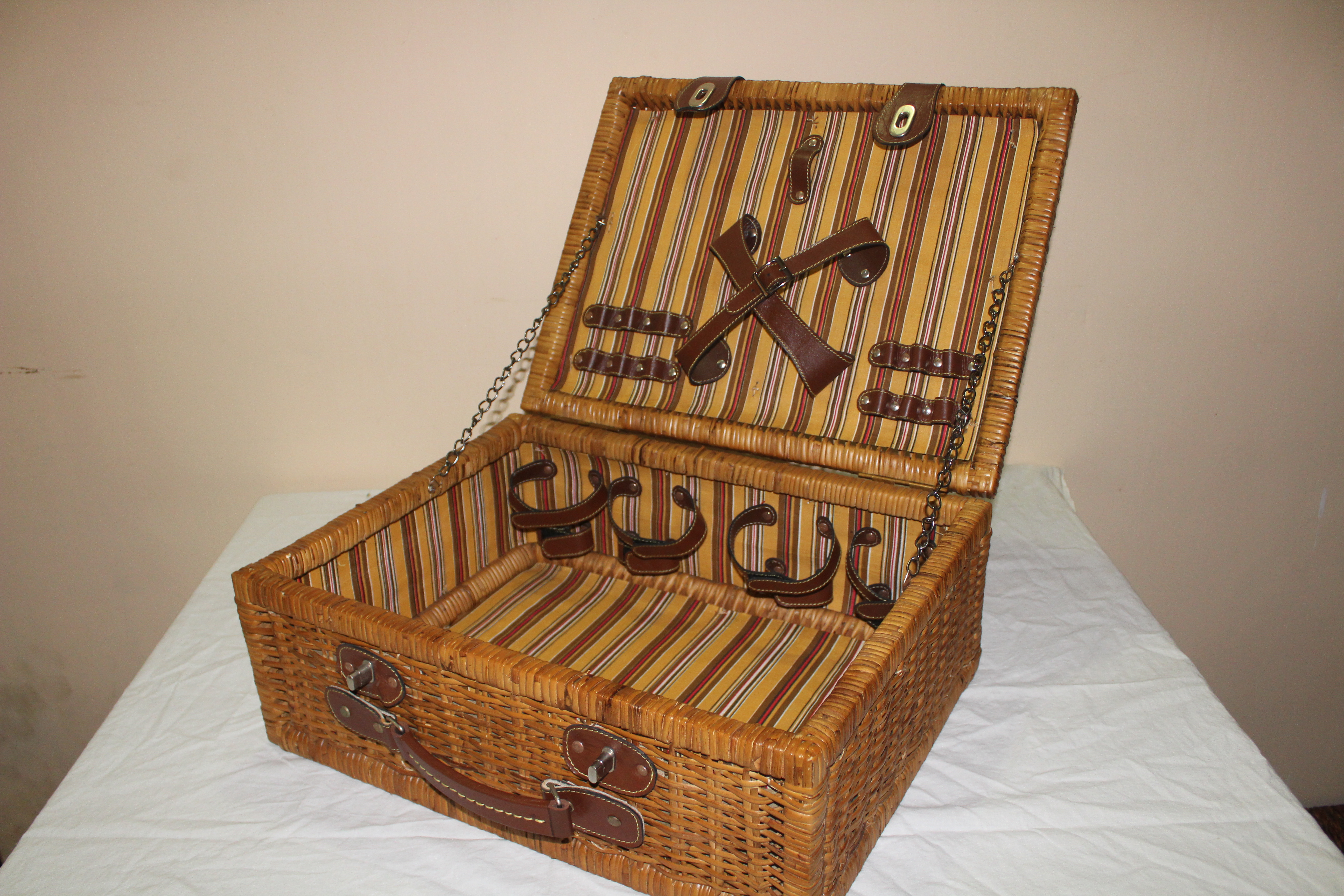 Decorated picnic basket made of cane, fitter with leather straps
